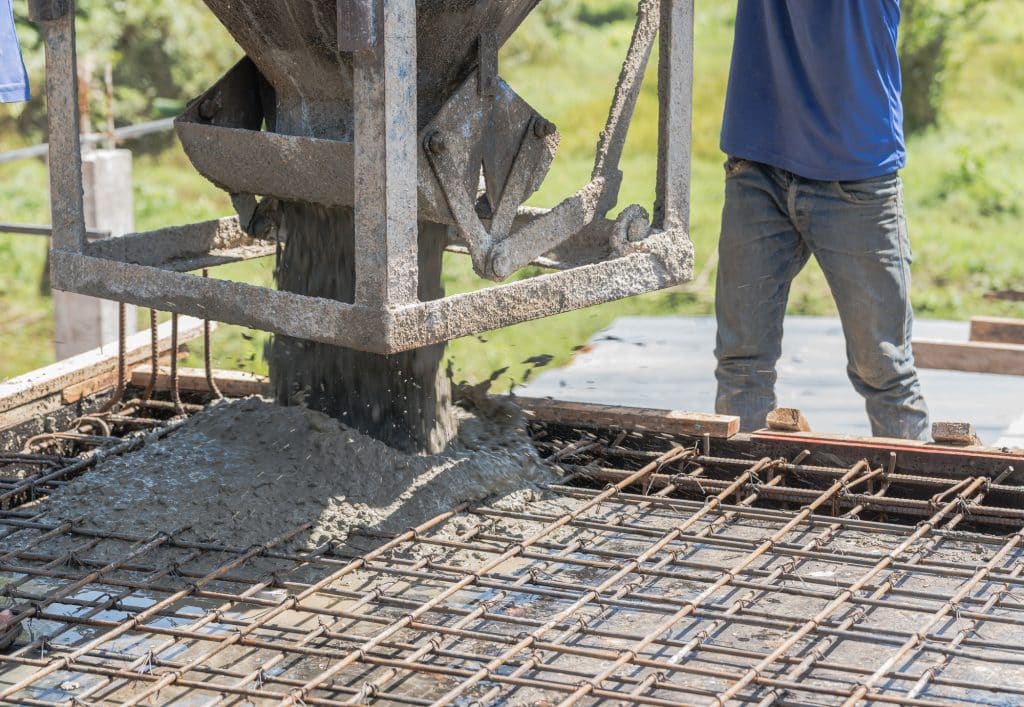 Worker open cement bucket tank machine on fence frame steel structure floor concrete building site